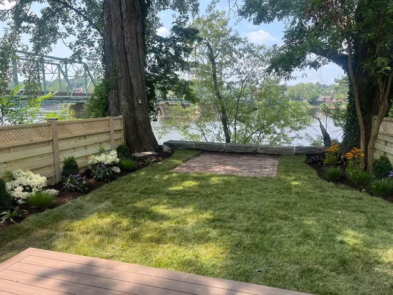 The Whole House on Lambert Lane — the riverfront backyard at 13 Lambert Lane with the New Hope-Lambertville Bridge visible through the trees.
