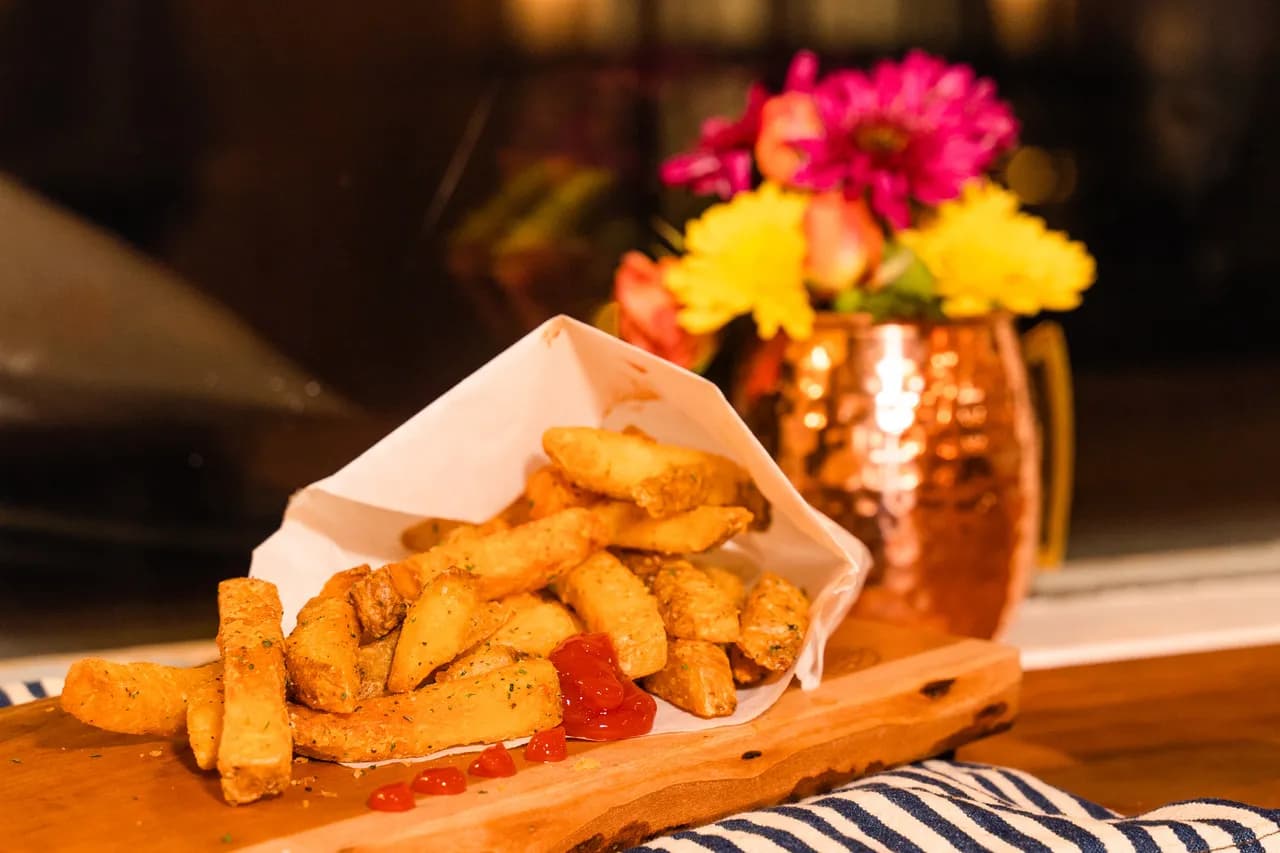 Couple 'o fries — double-fried, house-seasoned, in a paper cone on a live-edge board.